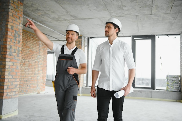 Engineer and worker checking project at building site background construction site at sunset in evening time