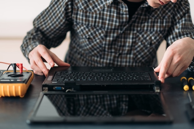 Photo engineer working on disassembled laptop