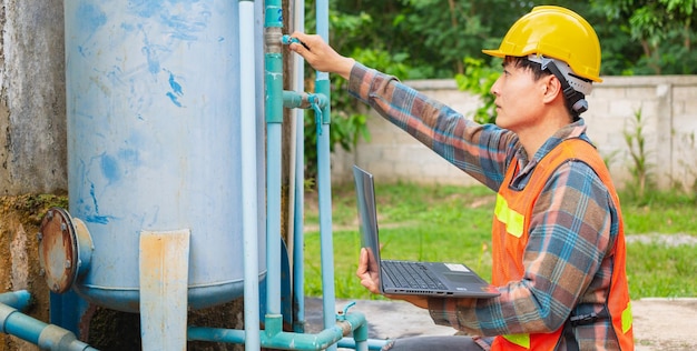 Engineer working in drinking water factory using a laptop computer to check water management system