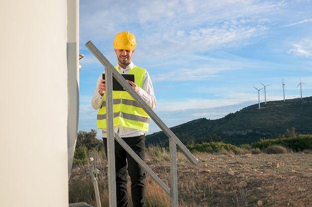 Engineer working and holding a tablet with the report in wind turbine farm Generator station renewable energy