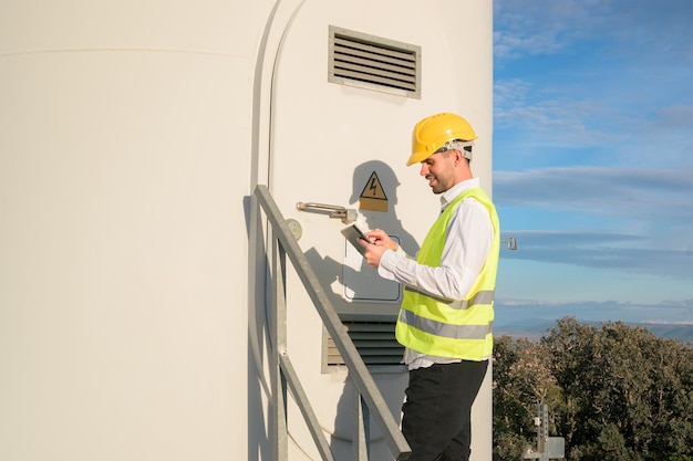 Engineer working and holding a tablet with the report in wind turbine farm Generator station renewable energy