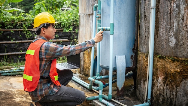 Engineer working using a laptop computer to check the water management system and boiler water pipe