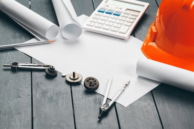 Engineer workplace with blueprints, compass, pencil and safety helmet