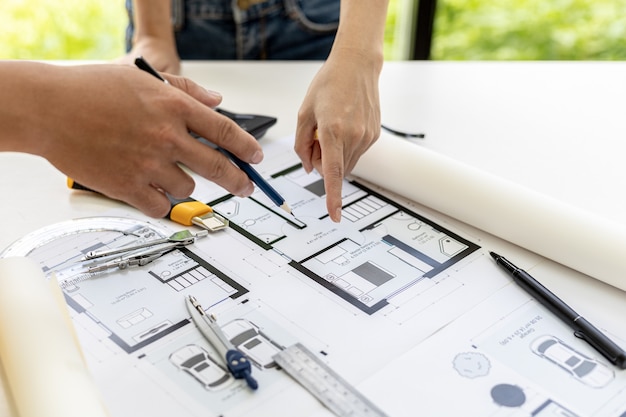 Photo engineers and architects pointing to the house blueprints designed for the client, meeting atmosphere, they meet together to plan the construction and fix it. design and interior design ideas.