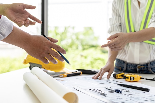 Photo engineers and architects pointing to the house blueprints designed for the client, meeting atmosphere, they meet together to plan the construction and fix it. design and interior design ideas.