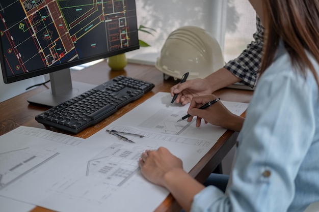 Engineers discuss a blueprint while checking information on a tablet computer in a office