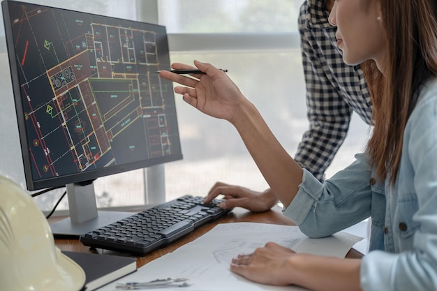 Engineers discuss a blueprint while checking information on a tablet computer in a office