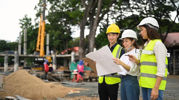 Engineers team wearing safety helmet and vest inspecting industrial building construction site Industry Engineer construction concept