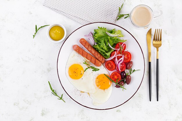 English breakfast fried eggs sausages tomatoes and olives American food Top view overhead copy space