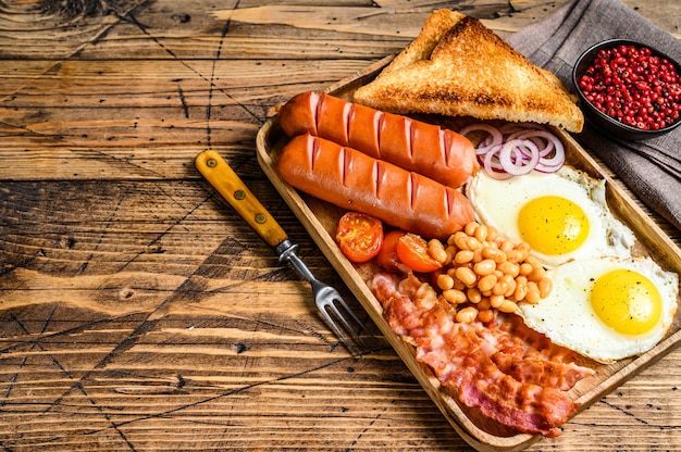 English Breakfast in a wooden tray with fried eggs, sausages, bacon, beans and toasts