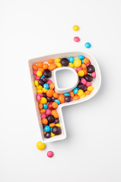 English letter P made from colorful candies on a white background