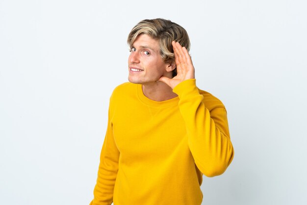 Photo english man over isolated white background listening to something by putting hand on the ear