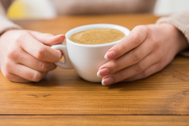 Enjoy cup of coffee. Woman hands closeup with aromatic espresso or americano on wood table