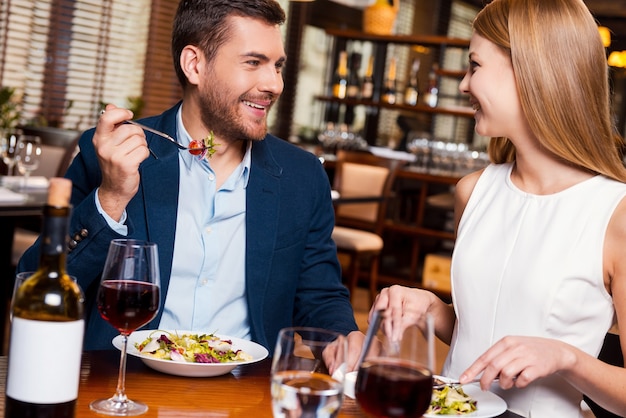 Enjoying meal together. Beautiful young loving couple enjoying dinner at the restaurant