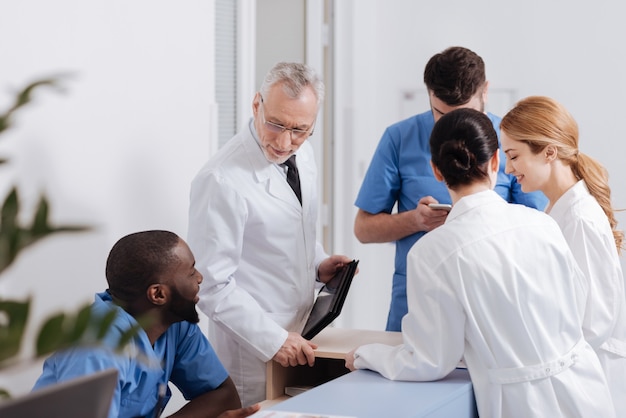 Enjoying morning routine at work. Lively positive involved medics having morning meeting in the clinic and expressing delight while sharing news