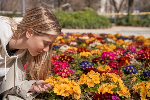 Enjoying spring's first blooms a young Caucasian woman gently touches a flower