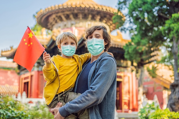 Enjoying vacation in china happy family in medical mask with national chinese flag in forbidden city