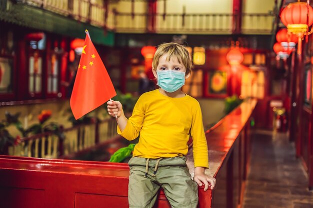 Enjoying vacation in china happy tourist boy in medical mask with a chinese flag on a chinese