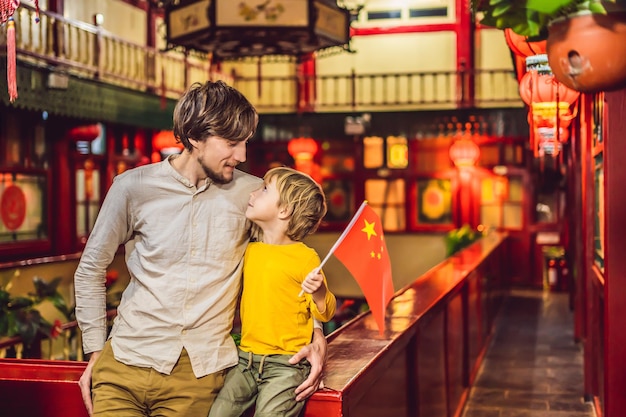 Enjoying vacation in china happy tourists dad and son with a chinese flag on a chinese background