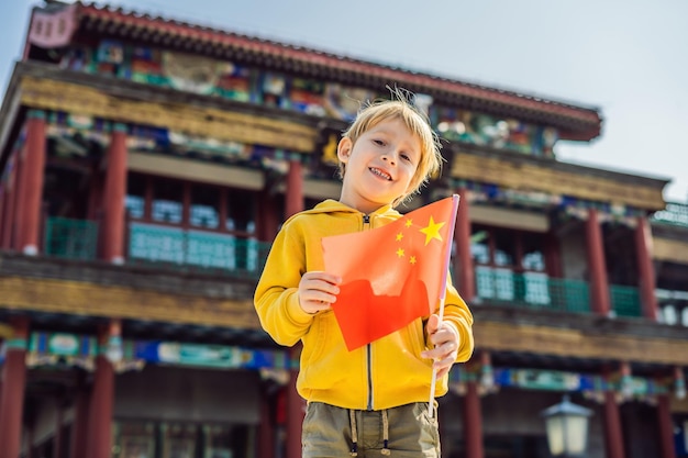 Enjoying vacation in China Young boy with national chinese flag on the background of the old Chinese street Travel to China concept Visa free transit 72 hours 144 hours in China