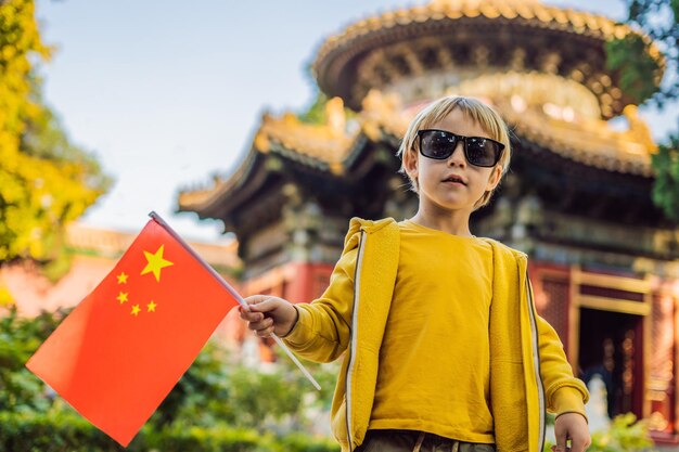 Enjoying vacation in China Young boy with national chinese flag in Forbidden City Travel to China with kids concept Visa free transit 72 hours 144 hours in China