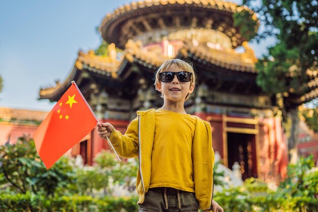 Enjoying vacation in China Young boy with national chinese flag in Forbidden City Travel to China with kids concept Visa free transit 72 hours 144 hours in China