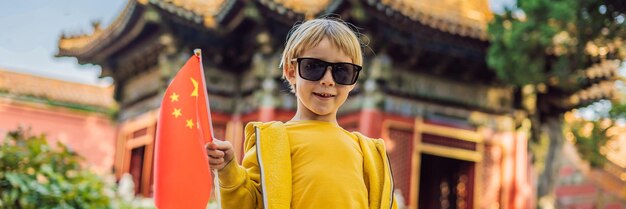 Enjoying vacation in china young boy with national chinese flag in forbidden city travel to china