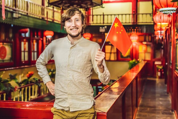 Enjoying vacation in China Young man with a Chinese flag on a Chinese background Travel to China concept Visa free transit 72 hours 144 hours in China