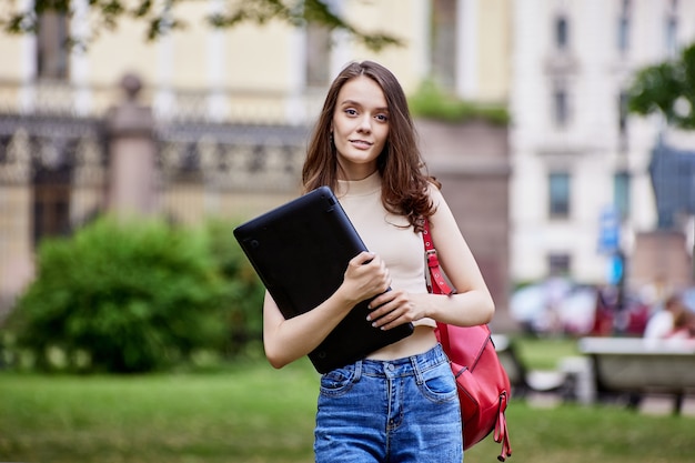 Enrollee is standing outdoors with laptop in hands