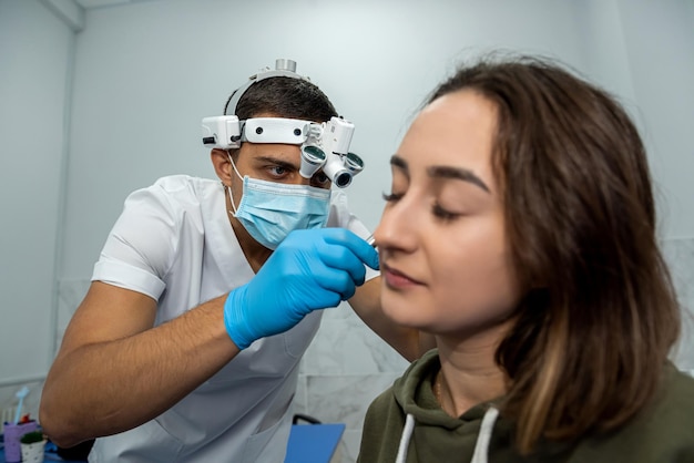 ENT doctor examines the ear with an otoscope of a female patient in the hospital