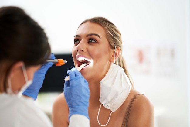 ENT specialist in mask chcecking up on her female patient