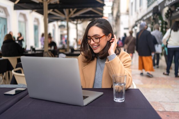 Enthusiastic happy carefree female student prepare freelance project sitting outdoor cafe