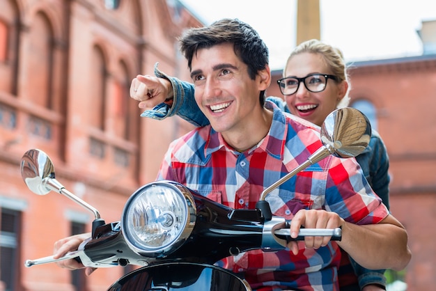 Enthusiastic young couple having scooter ride through Berlin