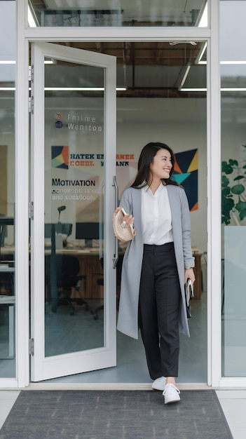 Entrance creative and asian woman opening a door to an office at a graphic design startup company v