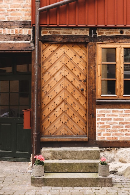 Photo entrance to and old building reinforced wooden door with some decorative flower pots on the stairs