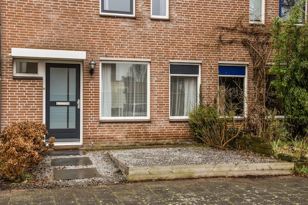 Entrance to a small residential brick house with a gravel terrace and various plants