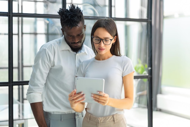 Entrepreneur african businessman and businesswoman discussing new business project in tablet in modern office