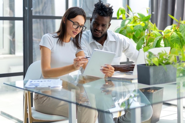 Entrepreneur african businessman and businesswoman discussing new business project in tablet in modern office