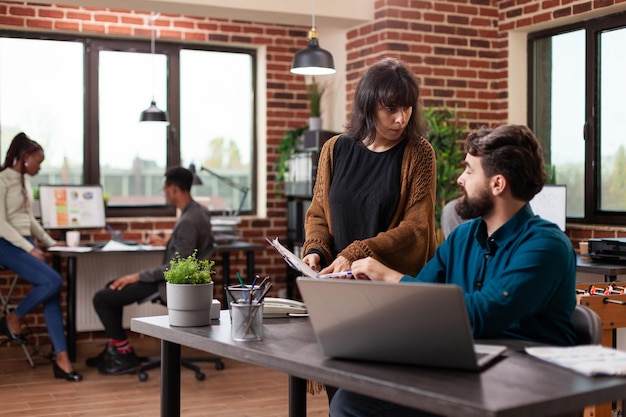 Entrepreneur people analyzing papers with marketing statistics discussing company strategy while working at business collaboration in brick wall startup office. Businesspeople brainstorming ideas