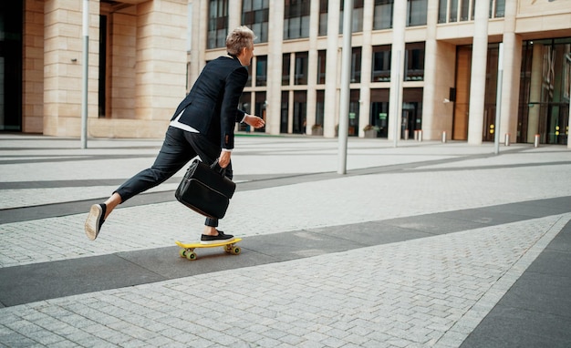 An entrepreneur rides a skateboard to work in the morning The lawyer holds a bag with documents