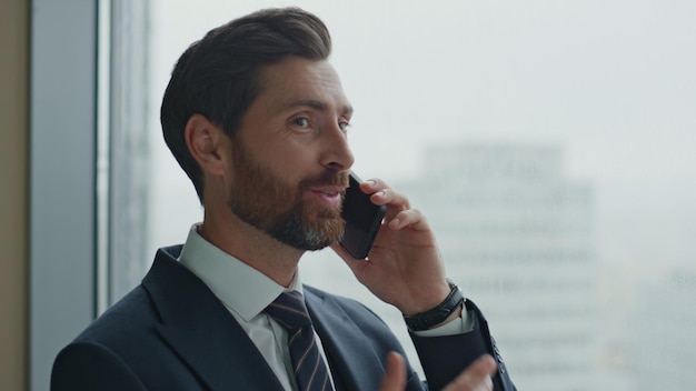 Entrepreneur speaking mobile phone near office window close up business talk