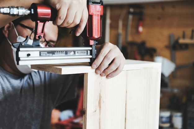 Entrepreneur  Woodwork holding a Tacker to assemble the wood pieces as the customer ordered.