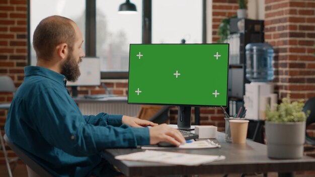 Photo entrepreneur working with green screen on computer to plan business project. employee using chroma key with isolated template and mockup background on monitor, designing strategy.