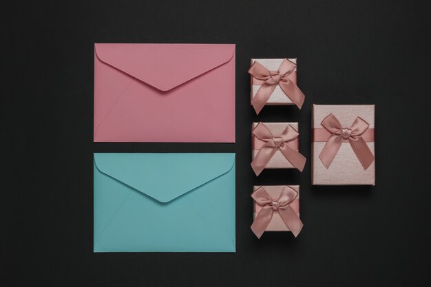 Envelope, boxes of gifts on black background. Christmas, Valentine's day, wedding or birthday. Top view