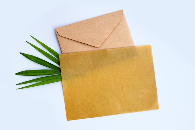 Envelope with blank paper on palm leaves on white background