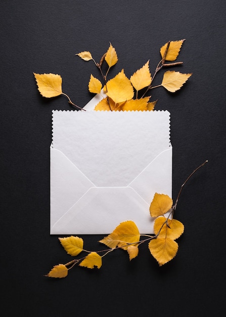 Envelope with a congratulation on a black background. Autumn card with fall foliage