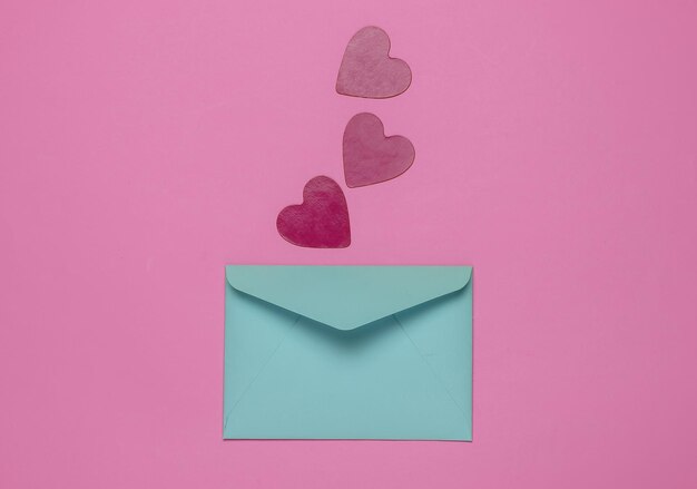 Envelope with decorative hearts on pink background Flat lay mockup for Valentines day wedding or birthday Top view