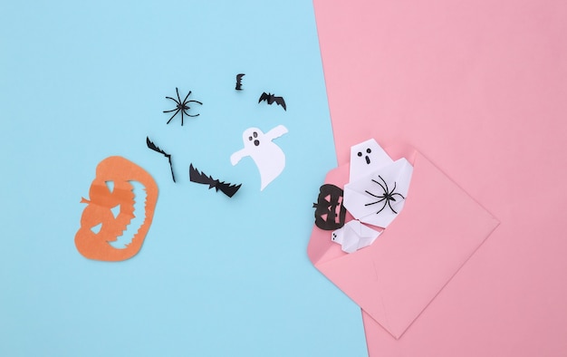 Envelope with handmade Halloween paper decor on pink blue pastel background. Halloween background. Top view