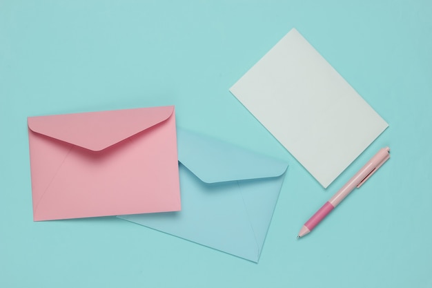 Envelope with a letter and pen on a blue pastel background. Valentine's day, wedding or birthday. Top view