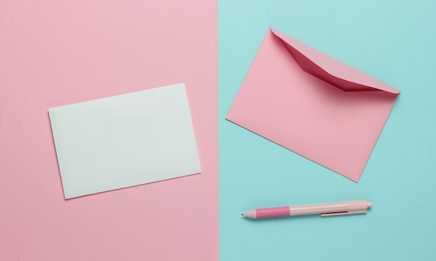 Envelope with a letter and pen on a blue pink pastel background. Valentine's day, wedding or birthday. Top view